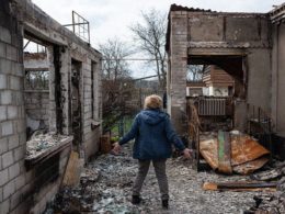 Жінка у селі Озера на Київщині стоїть в дворі свого зруйнованого будинку. Фото: Alexey Furman