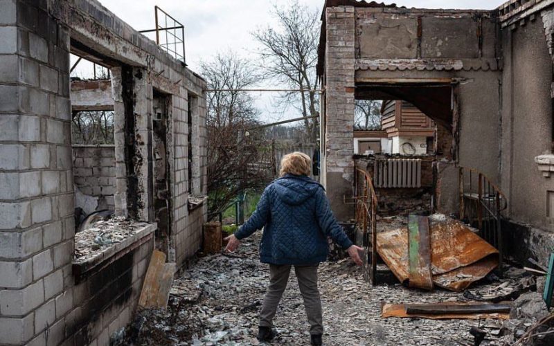 Жінка у селі Озера на Київщині стоїть в дворі свого зруйнованого будинку. Фото: Alexey Furman
