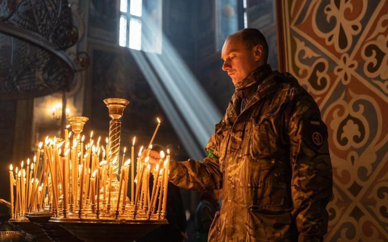 Український військовий запалює свічку у Михайлівському соборі у Києві. Фото: Serhii Korovainyi